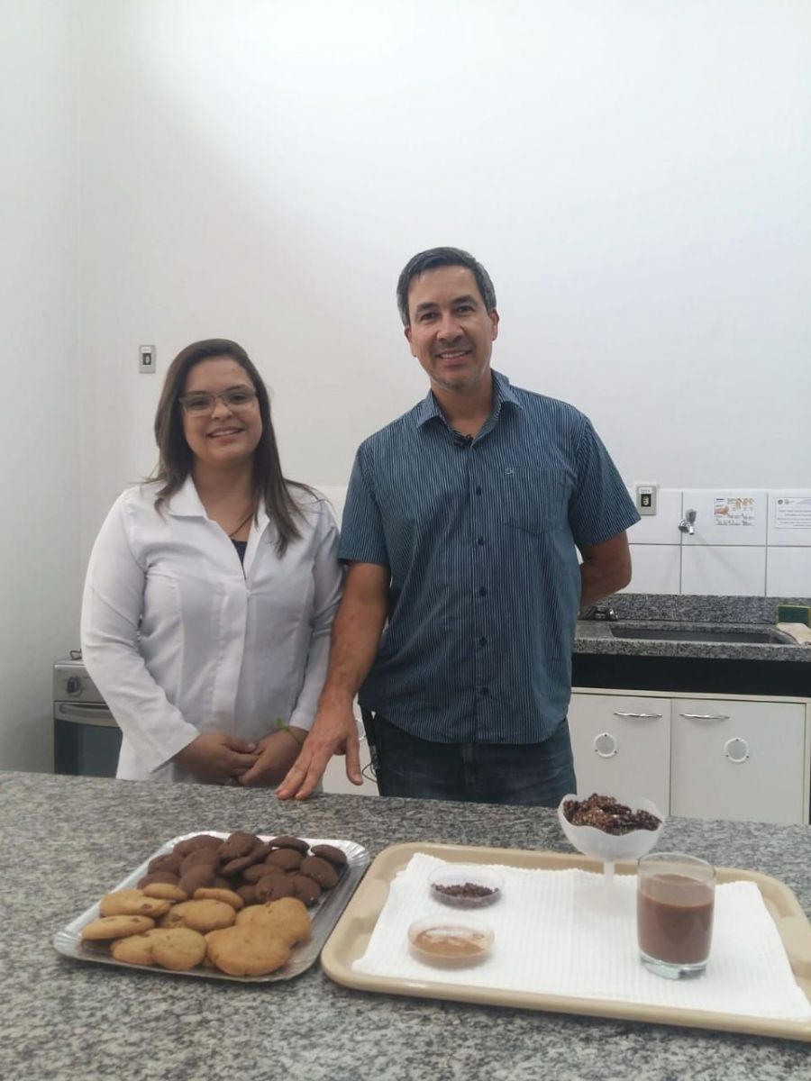 pesquisadora e professor Eduardo com cookies e outros produtos produzidos com a casca do cacau
