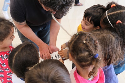 maestro mostra instrumento a crianãs participantes do projeto